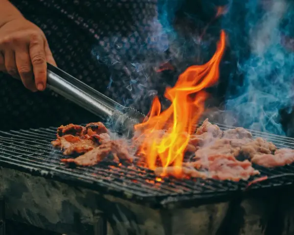 Carne a la parrilla, humeante y chispeante, lista para una deliciosa parrillada barbacoa.