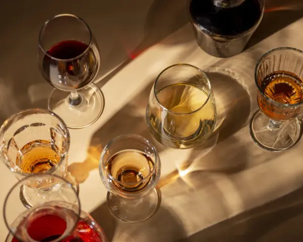 Copas de vino tinto y blanco, y una botella oscura, con reflejos de luz. El vino abierto se pone malo, mejor disfrutarlo pronto.