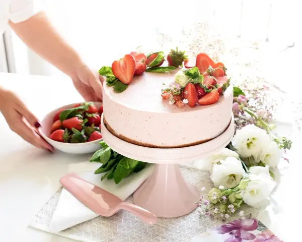 Deliciosa tarta de fresa decorada con fresas frescas y menta, lista para ser servida.