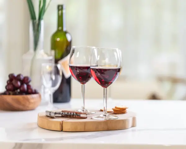 Dos copas de vino tinto, uvas y galletas, listas para disfrutar de un momento especial con los productos de la cooperativa do val.