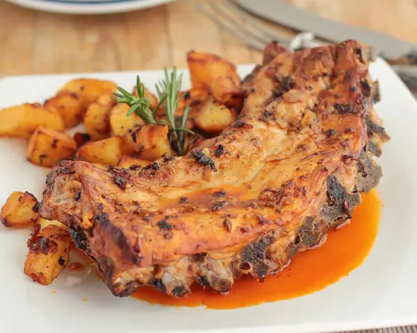 Costillas al horno con patatas doradas y romero fresco. Un plato jugoso y lleno de sabor.