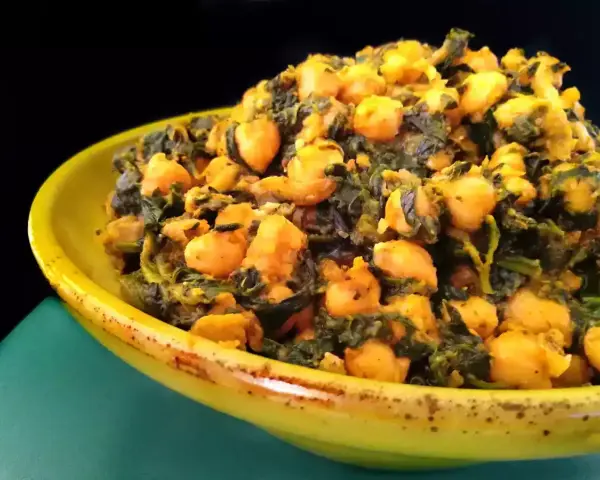 Un plato amarillo lleno de garbanzos con espinacas, un guiso saludable y sabroso.