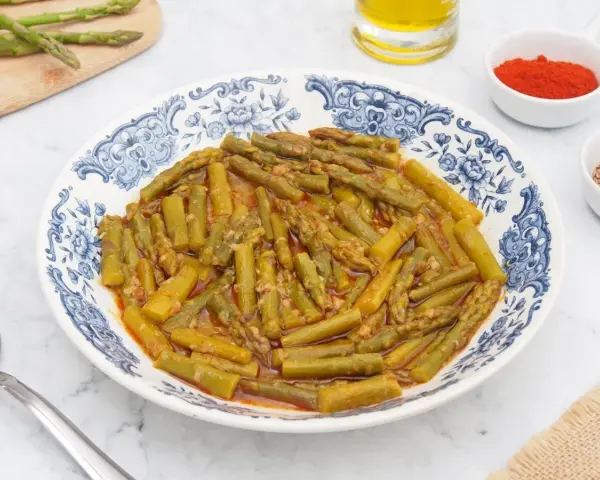 Espárragos esparragados en un plato con diseño azul y blanco, acompañados de pimentón y comino.