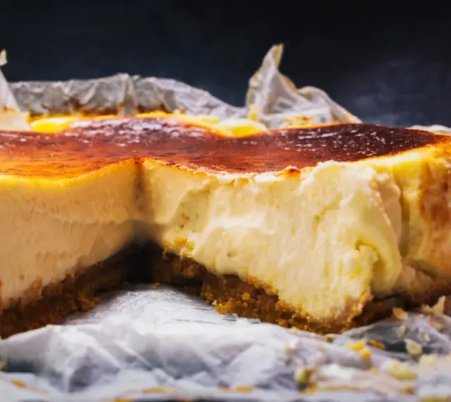 Tarta de queso cremosa con base crujiente y cobertura dorada, recién salida del horno.
