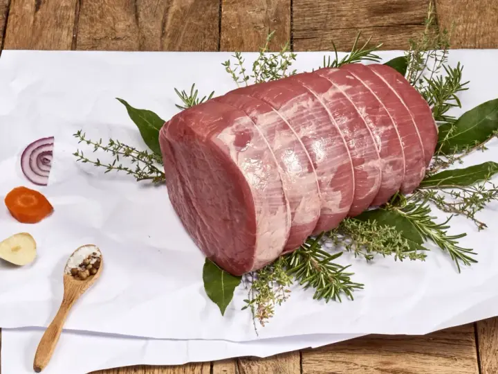 Un añojo ternera, parte de la pierna, listo para asar con hierbas aromáticas, cebolla, zanahoria y especias.