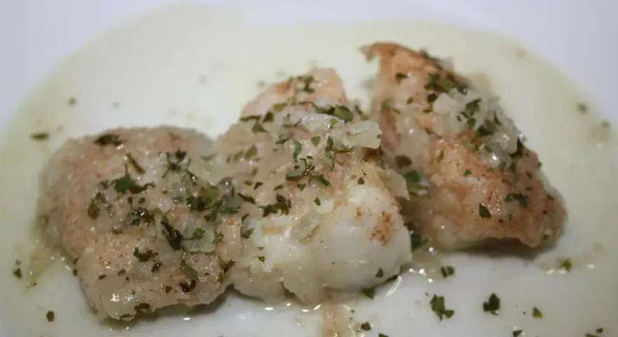 Tres trozos de bacalao en salsa verde, con perejil picado y trocitos de ajo.