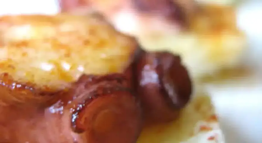 Tentáculos de pulpo a la plancha, dorados y jugosos, servidos sobre una base cremosa.