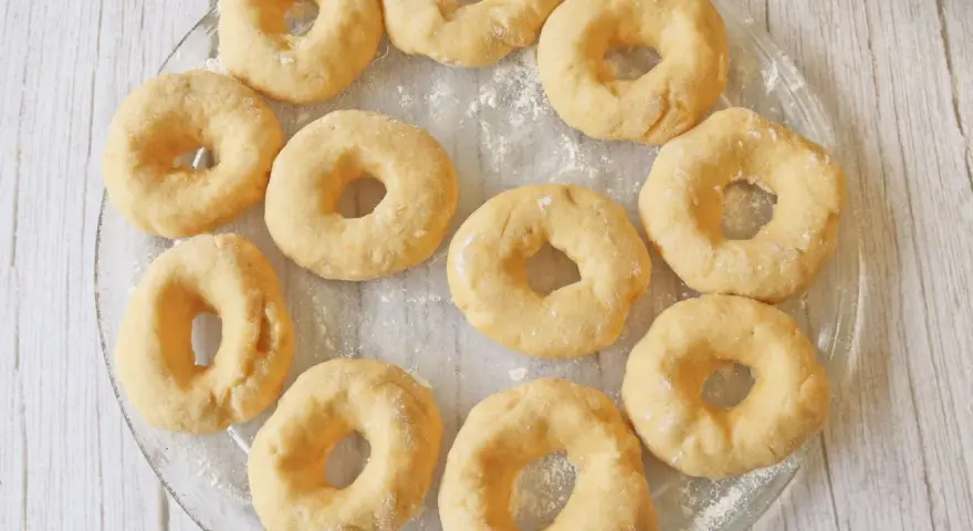 Un plato transparente muestra rosquillas caseras esponjosas, listas para hornear.