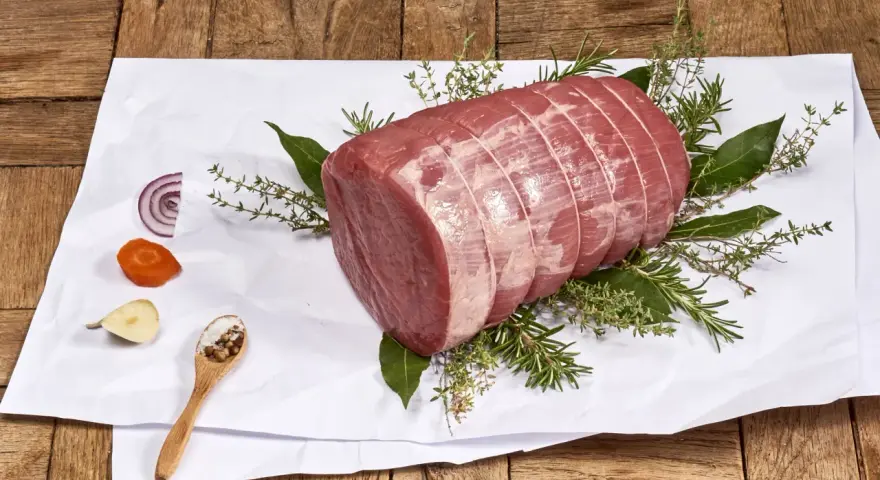 Un añojo ternera, parte de la pierna, listo para asar con hierbas aromáticas, cebolla, zanahoria y especias.