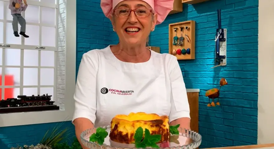 Eva Arguiñano sonríe mostrando una deliciosa tarta de queso casera, decorada con hojas de menta.