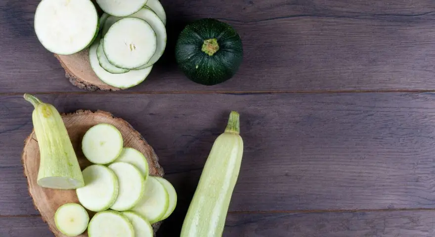 Rodajas de calabacín y calabacines enteros, listos para preparar deliciosas recetas con calabacín.