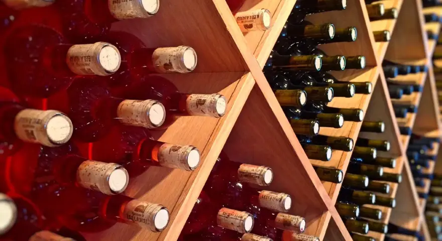 Estanterías de madera llenas de botellas de vino tinto y blanco. Un lugar donde se guarda el vino, listo para ser disfrutado.