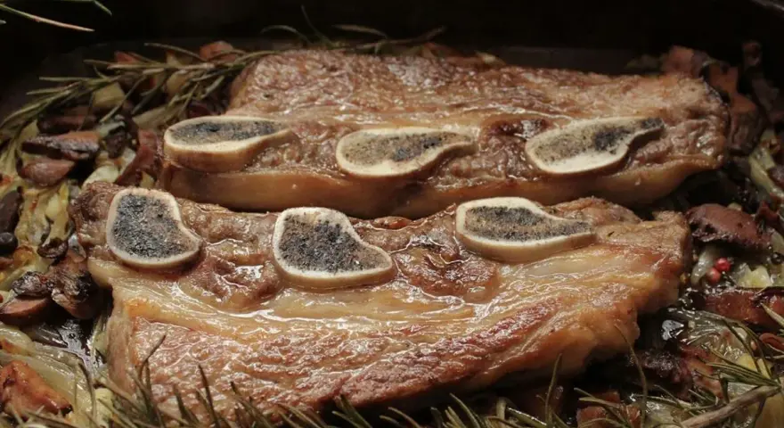 Ternera al horno jugosa, tierna y dorada, servida con champiñones, cebolla y romero fresco. ¡Un festín para los sentidos!