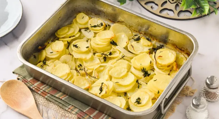 Patatas panaderas recién horneadas, doradas y tiernas, con cebolla y tomillo, listas para servir.