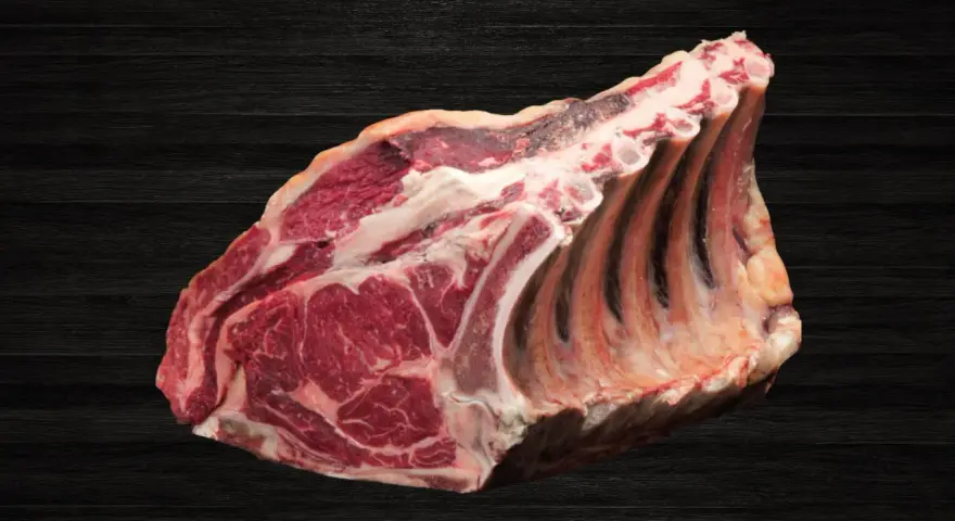Lomo bajo de vacuno crudo con costillas, sobre fondo oscuro de madera.
