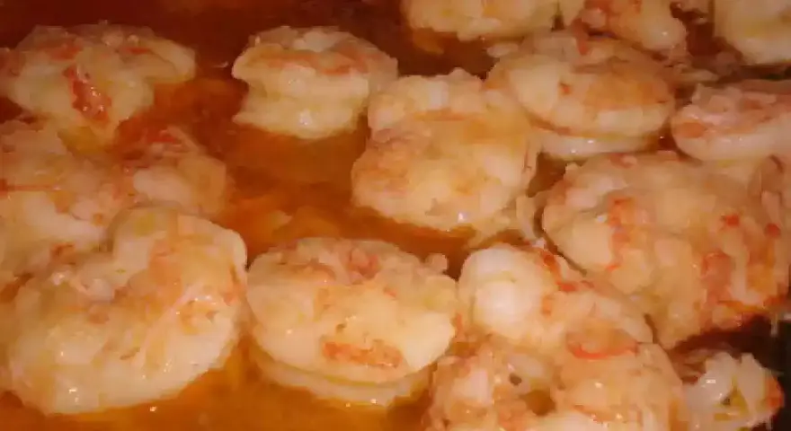 Gambas al pil pil burbujeando en aceite de oliva, listas para ser disfrutadas.
