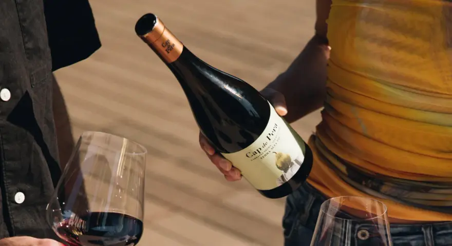 Manos sirven vino tinto de una botella Cap de Pera. Opiniones sobre "llàgrimes de tardor" y la experiencia.