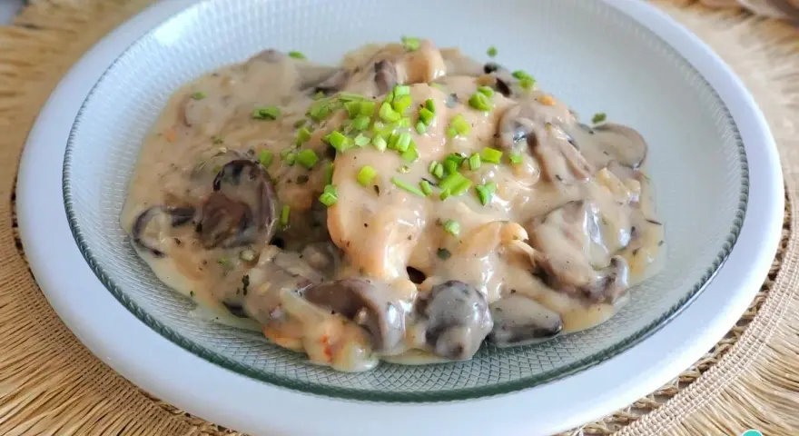 Pollo con champiñones en cremosa salsa de vino blanco, adornado con cebollino fresco. Un plato delicioso y reconfortante.