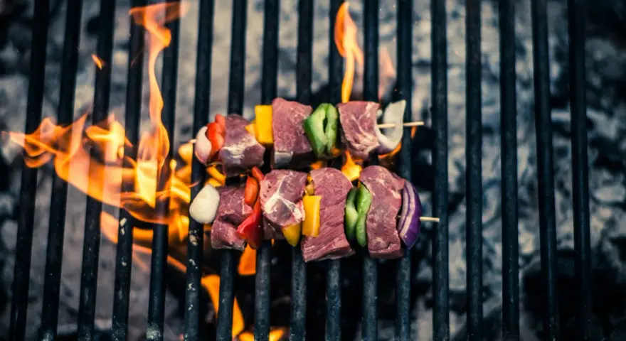 Brochetas de carne y verduras sobre una parrilla con llamas. Así es como se prepara una deliciosa barbacoa.