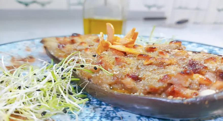 Berenjenas rellenas gratinadas con piñones y brotes frescos, un plato delicioso y nutritivo.