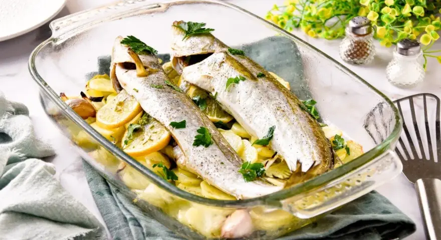 Pescadilla al horno con patatas, limón y ajo, recién salida del horno. Un plato sencillo y delicioso.