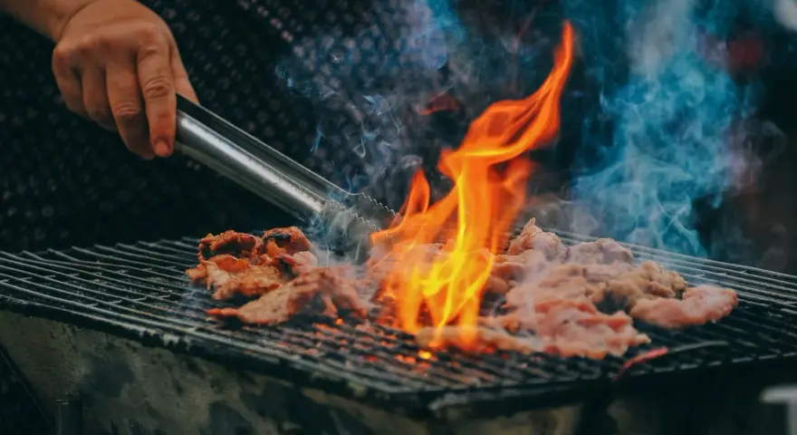 Carne a la parrilla, humeante y chispeante, lista para una deliciosa parrillada barbacoa.