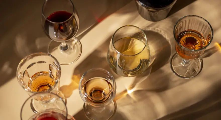 Copas de vino tinto y blanco, y una botella oscura, con reflejos de luz. El vino abierto se pone malo, mejor disfrutarlo pronto.
