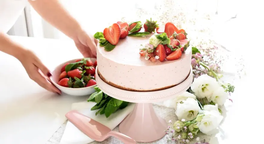 Deliciosa tarta de fresa decorada con fresas frescas y menta, lista para ser servida.