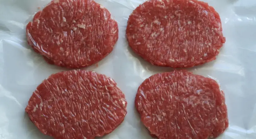 Cuatro hamburguesas de carne poco hecha, listas para cocinar y disfrutar.
