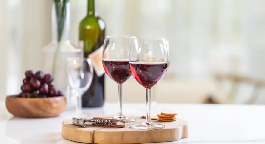 Dos copas de vino tinto, uvas y galletas, listas para disfrutar de un momento especial con los productos de la cooperativa do val.
