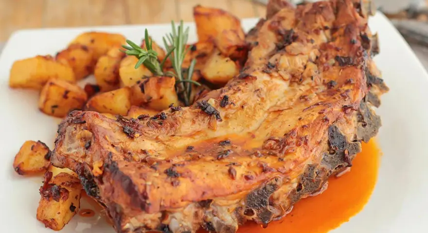 Costillas al horno con patatas doradas y romero fresco. Un plato jugoso y lleno de sabor.