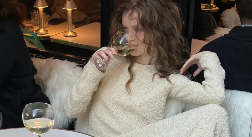 Mujer disfruta de los beneficios del vino blanco en un ambiente acogedor.