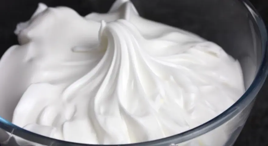 Merengue italiano esponjoso y brillante en un bol de cristal, listo para decorar postres.