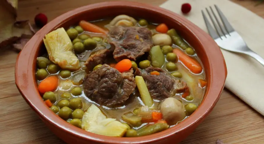 Menestra de verduras con carne, un plato reconfortante con trozos de carne tierna, guisantes, zanahorias y judías verdes en un caldo sabroso.