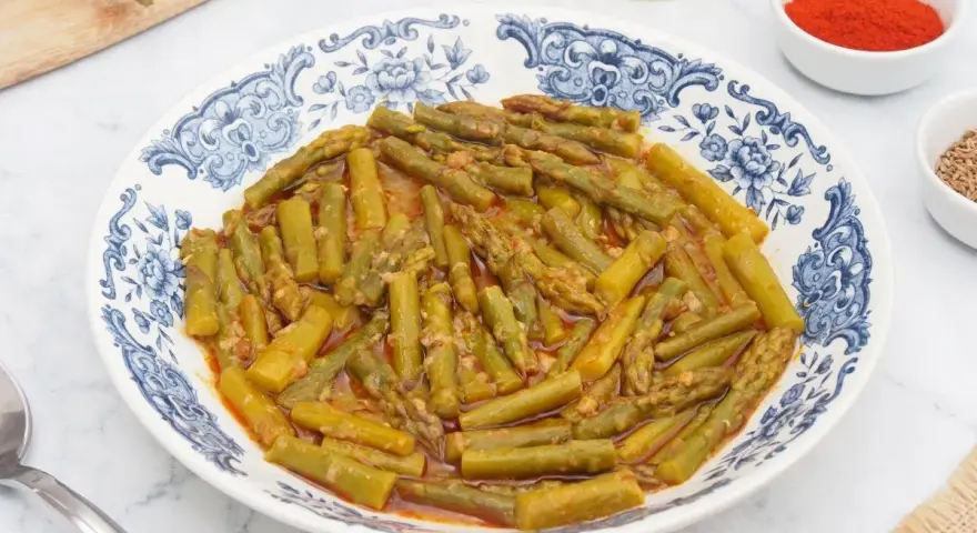Espárragos esparragados en un plato con diseño azul y blanco, acompañados de pimentón y comino.