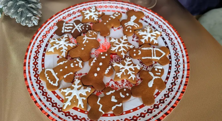 Plato con galletas de jengibre decoradas con glaseado blanco, con formas de hombrecitos, estrellas y copos de nieve. ¡Perfectas para la temporada navideña!