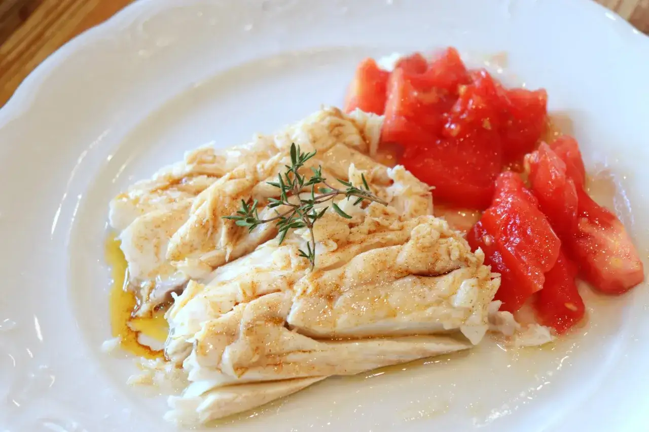 Deliciosa lubina a la sal, tierna y jugosa, servida con tomates frescos y un toque de romero.