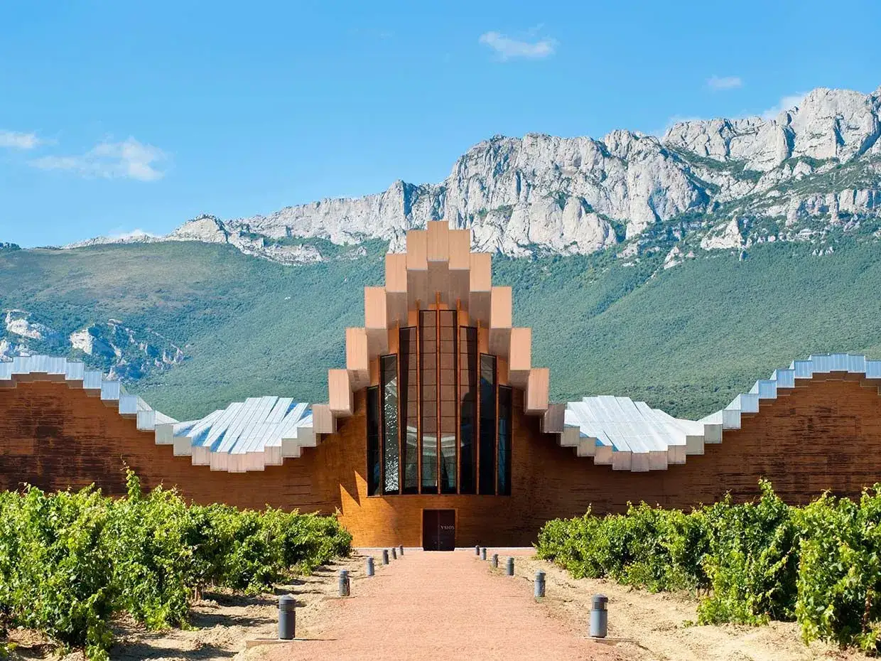 Bodega moderna rodeada de viñedos, con montañas al fondo. Un lugar ideal para degustar los mejores vinos de la Rioja Alavesa.