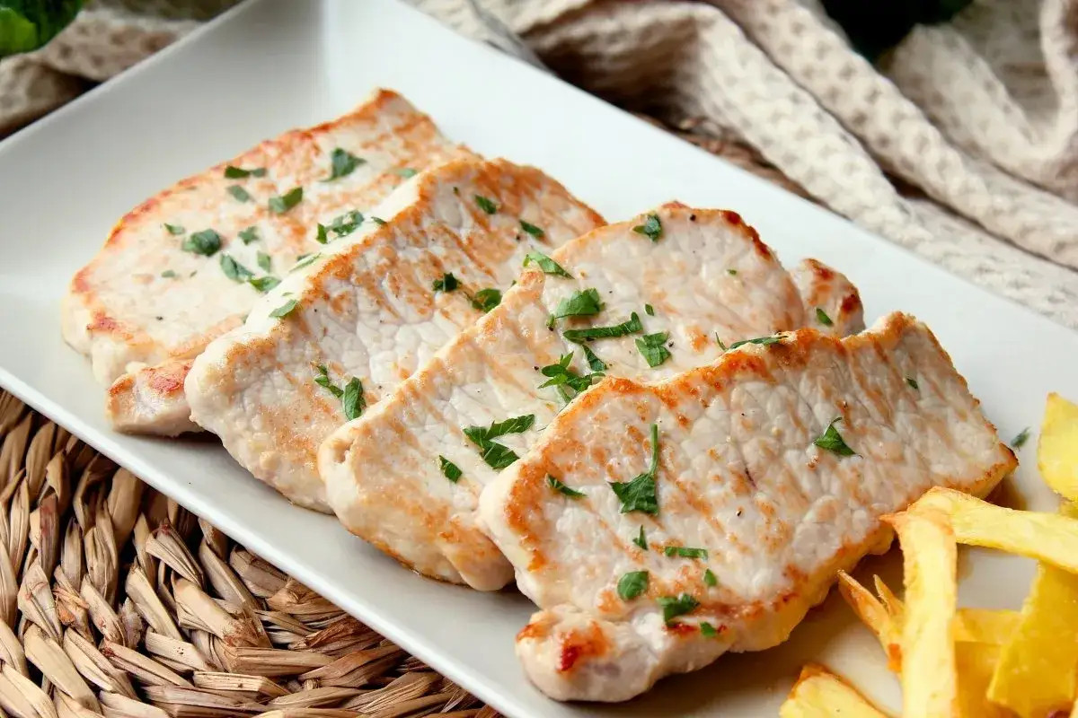 Cuatro filetes de lomo de cerdo, dorados y espolvoreados con perejil, listos para saber cuántos entran en un kilo.