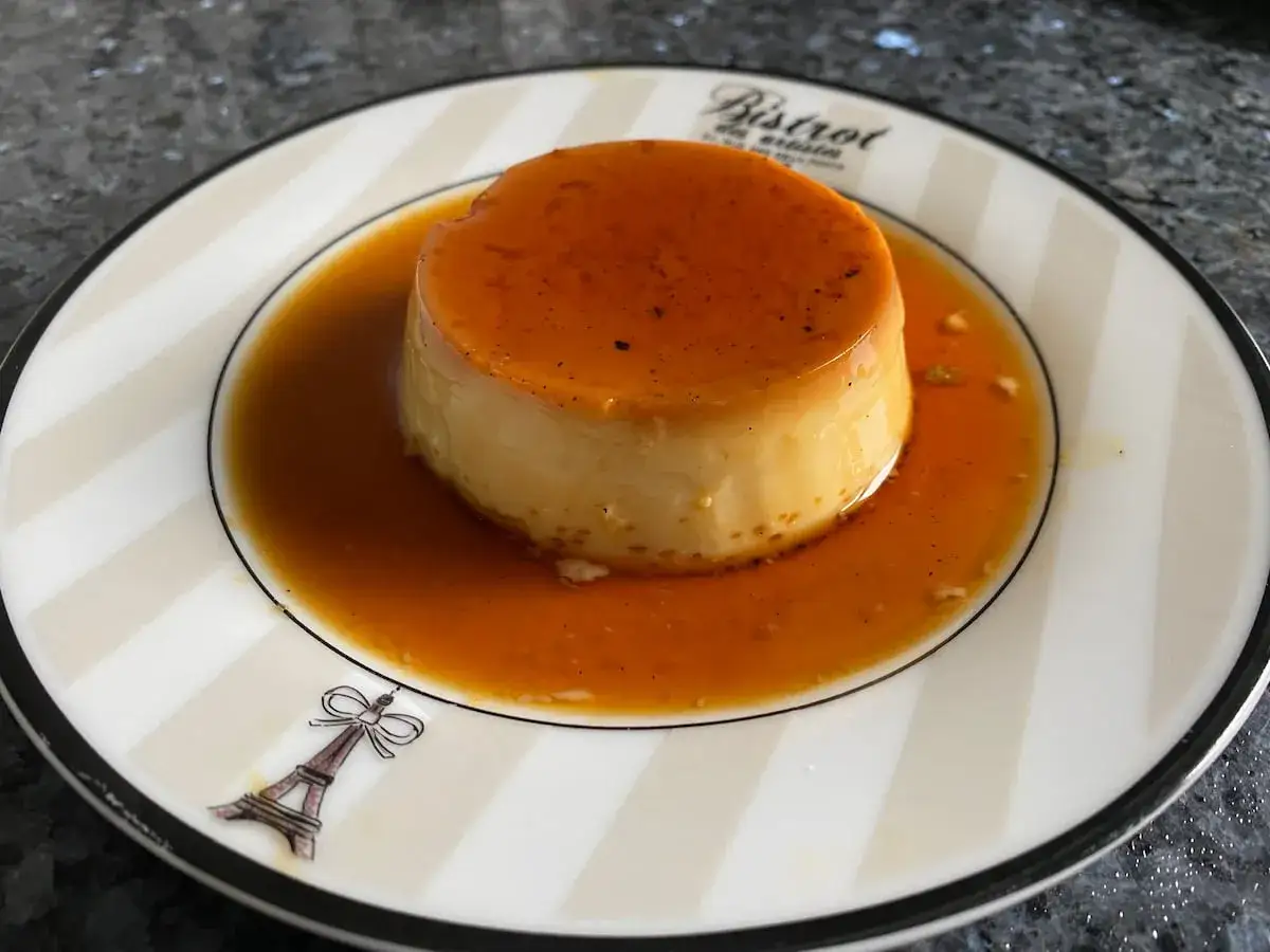 Delicioso flan de queso con caramelo líquido, servido en un plato con diseño de Torre Eiffel.