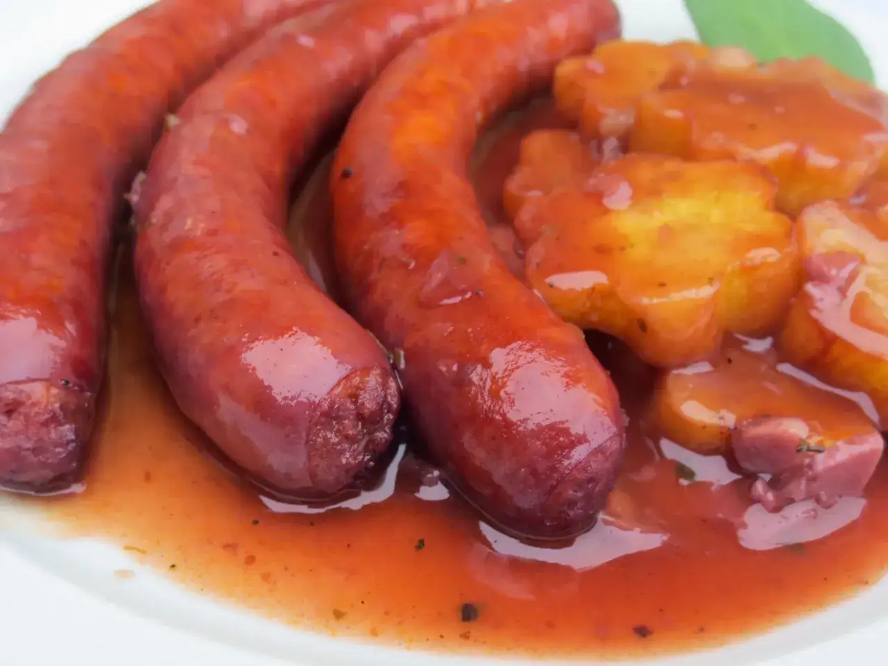 Salchichas al vino Monsieur Cuisine, jugosas y doradas, servidas con patatas en salsa roja.