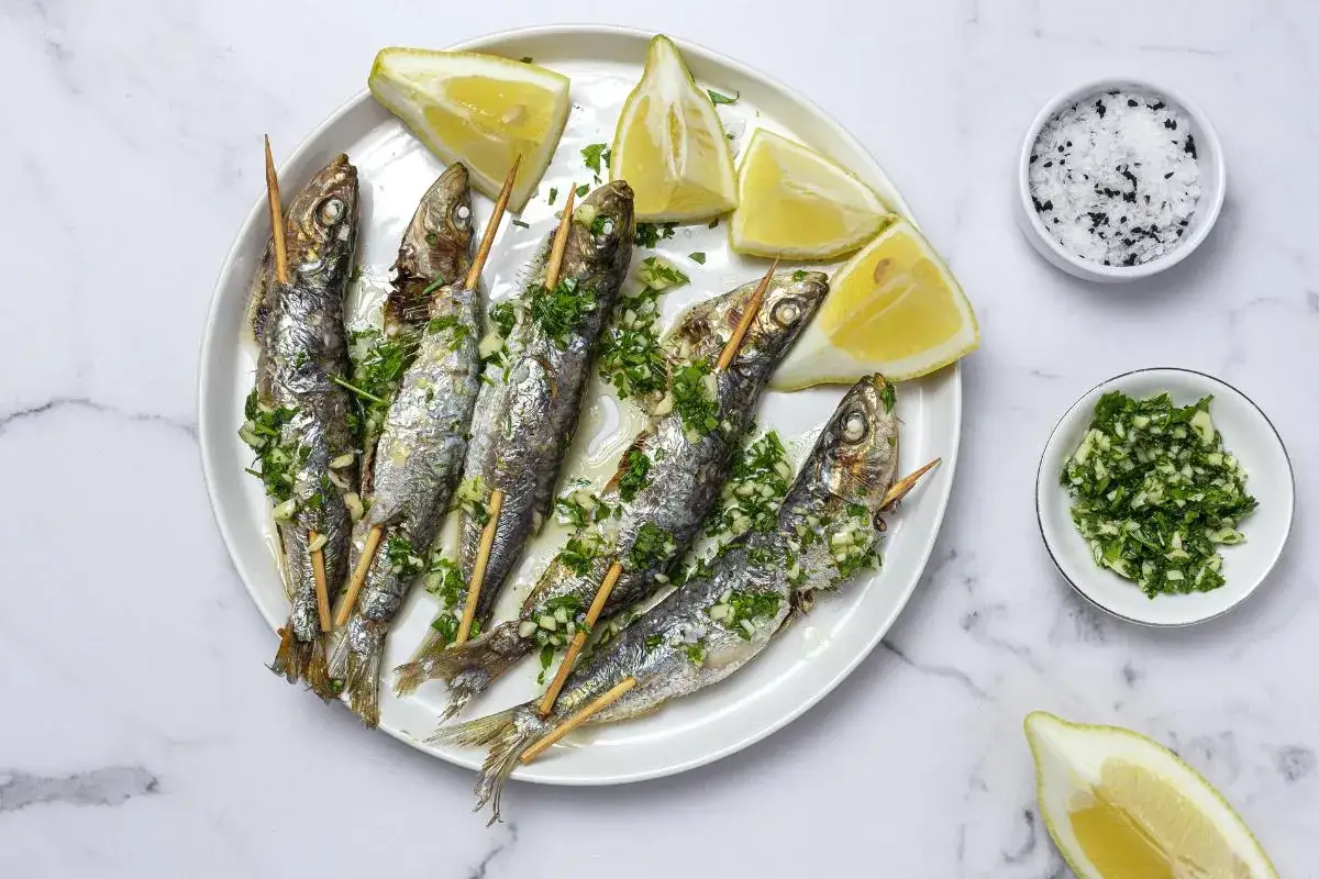 Deliciosas sardinas al horno, servidas con limón y perejil picado. Un plato sencillo y sabroso.