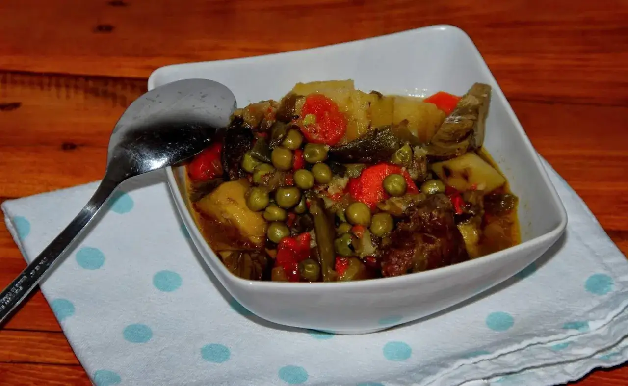 Un reconfortante plato de menestra de verduras con carne, lleno de guisantes, zanahorias y patatas.
