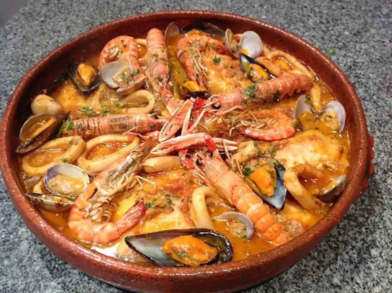 Una generosa zarzuela de pescado rebosante de gambas, mejillones, almejas y calamares en una rica salsa.