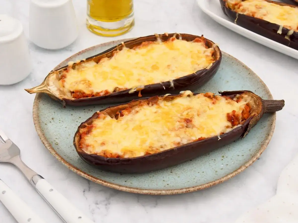 Dos mitades de berenjenas rellenas de atún, gratinadas con queso derretido, listas para disfrutar.