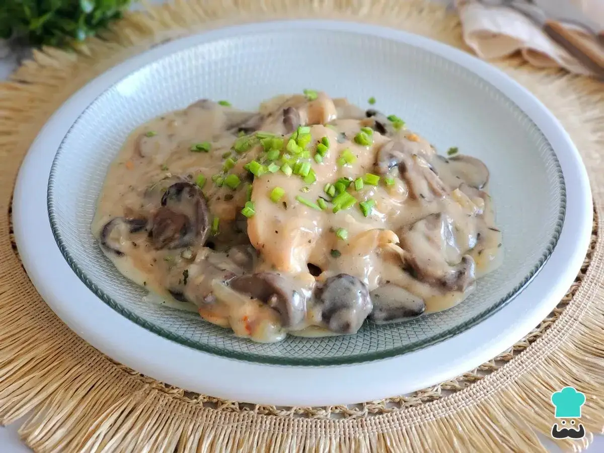 Pollo con champiñones en cremosa salsa de vino blanco, adornado con cebollino fresco. Un plato delicioso y reconfortante.