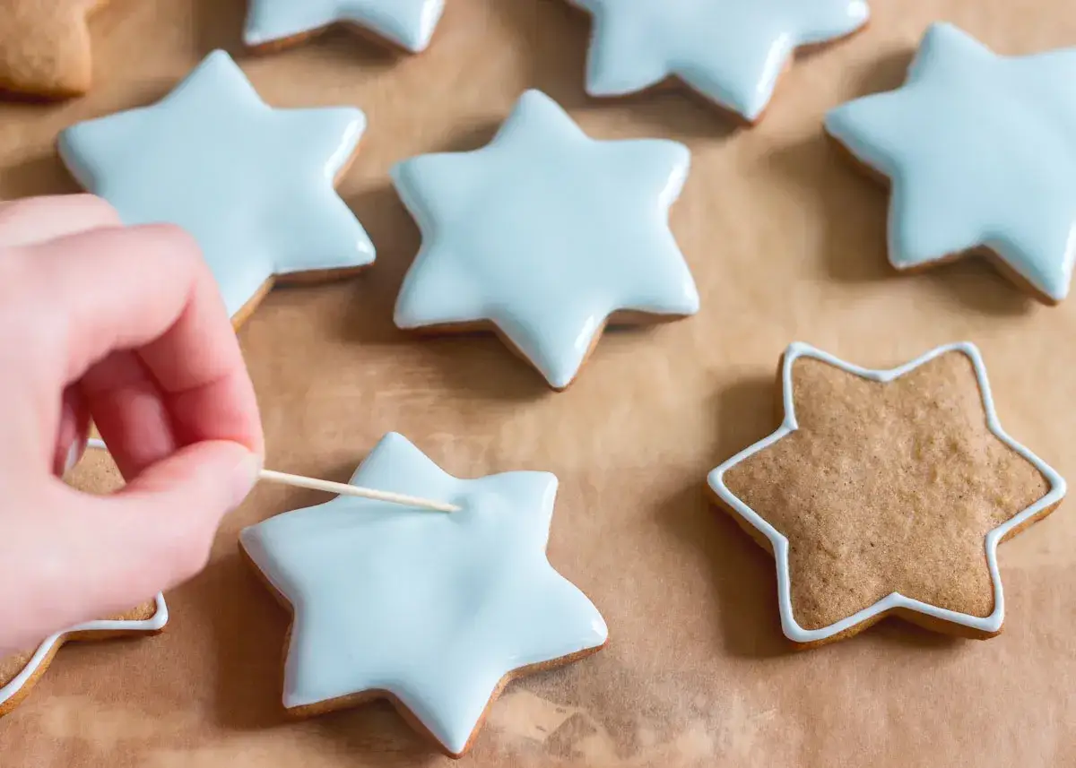 Decorando galletas de jengibre con glaseado azul claro en forma de estrella.