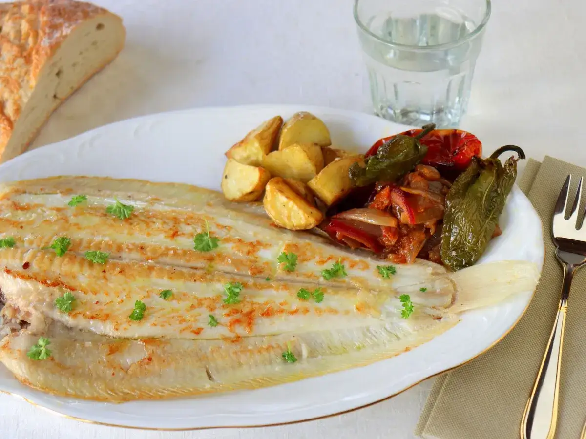 Un delicioso lenguado a la plancha, acompañado de patatas asadas y pimientos.