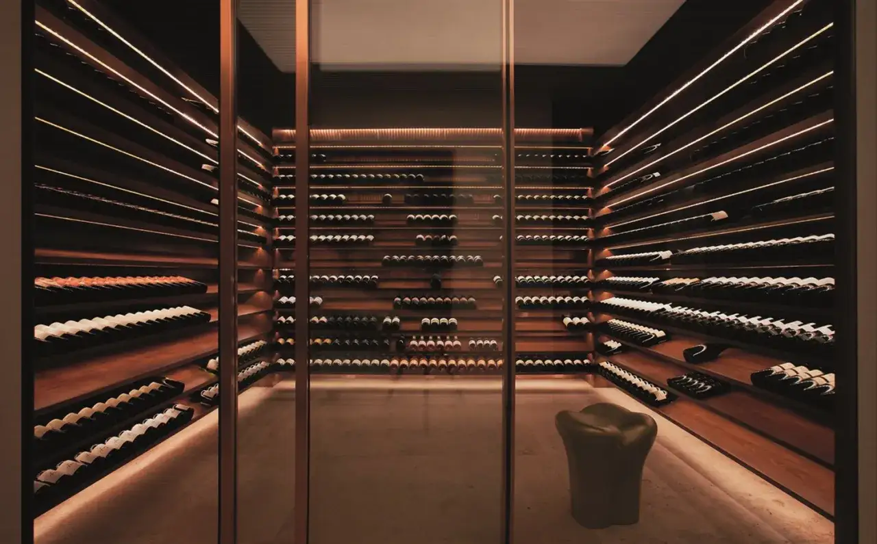 Impresionante lugar donde se guarda el vino, con estanterías de madera repletas de botellas y una iluminación tenue y elegante.