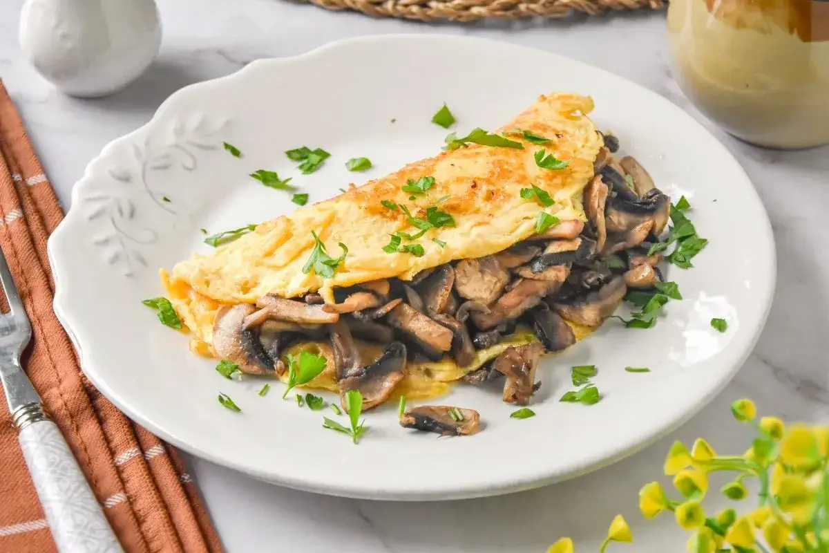 Tortilla dorada rellena de champiñones salteados, una de las mejores recetas con champiñones. Decorada con perejil fresco.